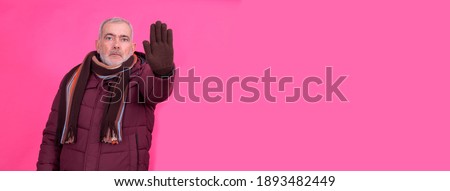 senior man with anorak and stop gesture in hand, concept of denial or reproach to the cold and viruses
