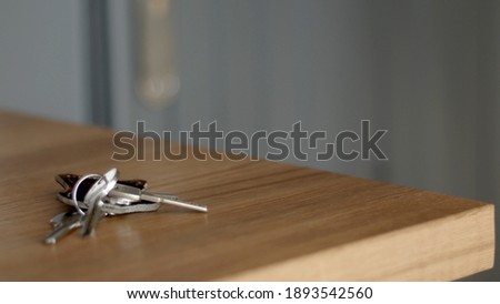 Bunch of keys on a wood light table. Grey wall blur on the background. Minimal close-up high-quality photo.