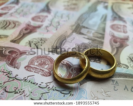 A pair of gold rings placed on a Afghanistan banknote represent love.Valentine Day, wedding gold ring. 