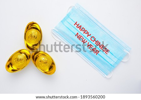 A picture of Happy Chinese New Year on face mask and gold ingot with the word prosperity in Chinese on it. People are struggle to search for prosperity during Covid-19.
