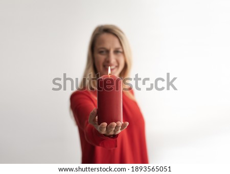 Red big candle holding by young woman. Girl wearing red blouse on white background. In Valentine day get a gift. Memory day. Love and cherish.