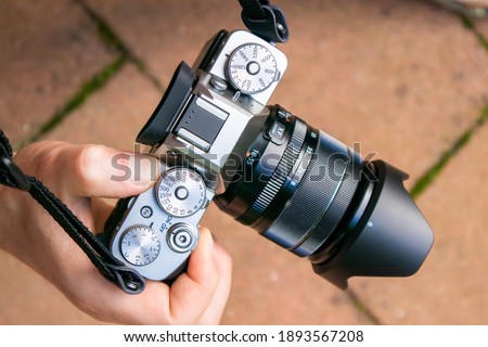 Closeup of a mirrorless camera body with lens held by a person hand Royalty-Free Stock Photo #1893567208