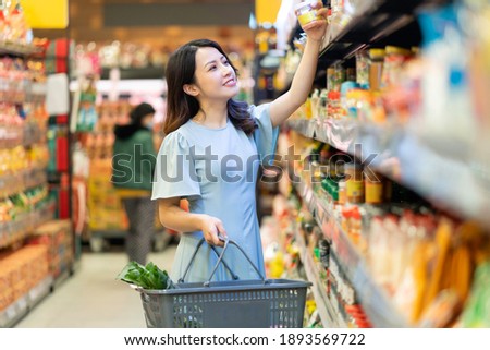 Young girl is choosing to buy foodstuffs at the supermarket Royalty-Free Stock Photo #1893569722