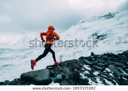 Woman trail runner cross country running up to winter snow mountain top Royalty-Free Stock Photo #1893591082