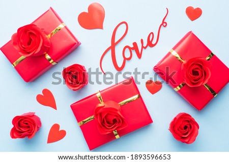 Valentine day composition, Greeting gift box with confetti hearts and roses on blue background. Flat lay
