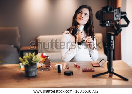 Beauty blogger nice female filming daily make-up routine tutorial on camera. Influencer young woman live streaming cosmetics product review in home studio. Vlogger job. DIY putting makeup Royalty-Free Stock Photo #1893608902
