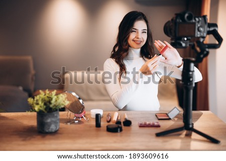 Beauty blogger pretty female filming daily make-up routine tutorial on camera. Influencer young woman live streaming cosmetics product review in home studio. Vlogger job. DIY. Royalty-Free Stock Photo #1893609616
