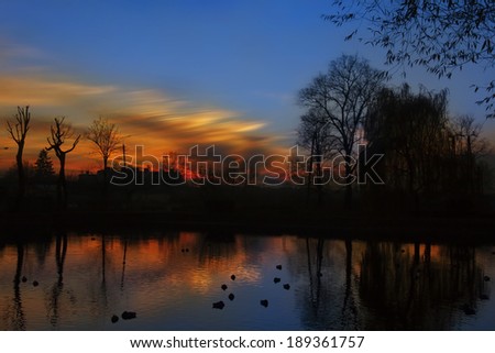 sunset over the city park in the shadow of sleeping ducks on the water 