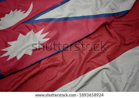 waving colorful flag of indonesia and national flag of nepal. macro