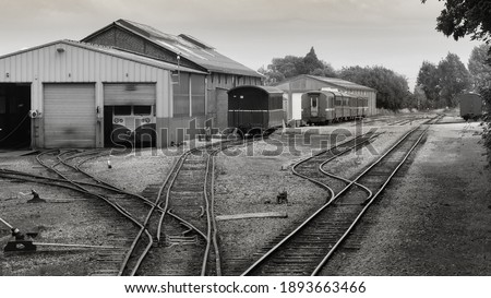 Small isolated station in a French countryside. Railways, rails, hangars and station buildings. Parked wagons and locomotive. Old train stationary. Vintage black and white photo