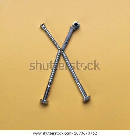 Alphabet letter X made of bolts, screws. Symbols on yellow plain background