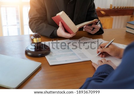 Lawyer hands holding a legal book and clarify the law to client while  sign a contract at lawyer office