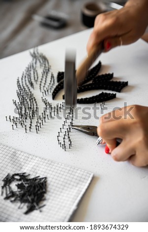 Tools for string art. Making proccess of picture made with threads and nails. Woman hands twisting the threads around the nails. String art creative design. Soft focus on details. Interior decoration.