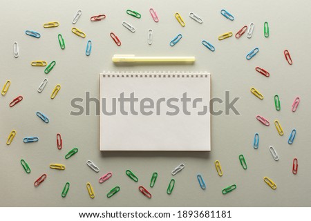 Open spiral notepad on gray background , notebook and pen lie on textural paper, flat lay concept in trendy colors of the year, paper clips of different colors