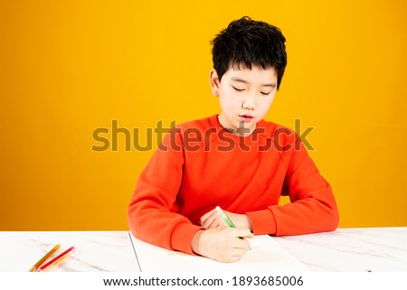Little boy drawing a picture with colored pencils on a sketchbook