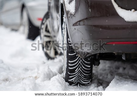 rear view of car with winter tyres in snowy road, close-up Royalty-Free Stock Photo #1893714070