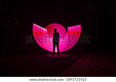 one person standing against beautiful pink circle light painting as the backdrop