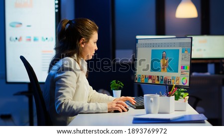 Professional woman photo retoucher working on a big project in business office at night time. Content creator doing portrait retouching using performance laptop, artist, occupation, screen, graphic