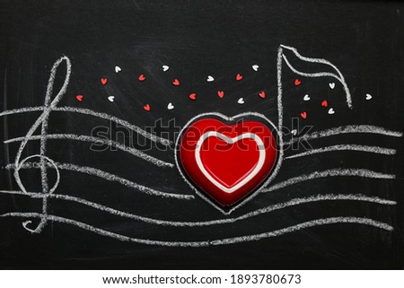 Red heart on a chalk board. Valentine's Day. Lovers love melody. Song of romance in illustration, figure. Stave, clef on a black background.