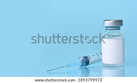 Vaccine in a bottle with a syringe on a blue background.The concept of medicine, healthcare and science.Coronavirus vaccine.Copy space for text.Banner Royalty-Free Stock Photo #1893799972