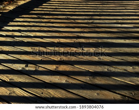 Outdoor wooden floor under sunset. Shadow lines, wood planks in the sunset design for a natural and calm background (selective focus)