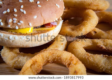 Delicious freshly prepared burger and onion rings on the table. Fast food