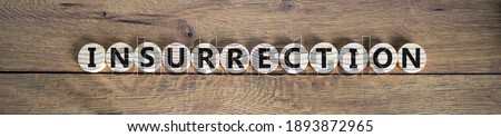 Insurrection symbol. Wooden circles with the word 'insurrection'. Beautiful wooden background, copy space. Business and insurrection concept.