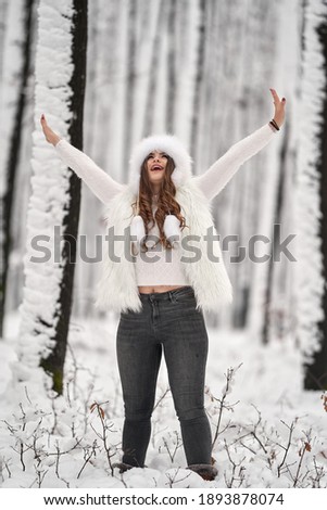 Young caucasian woman having fun playing in the snow in the forest