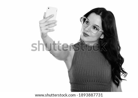 Studio shot of young beautiful Spanish woman taking selfie picture with mobile phone