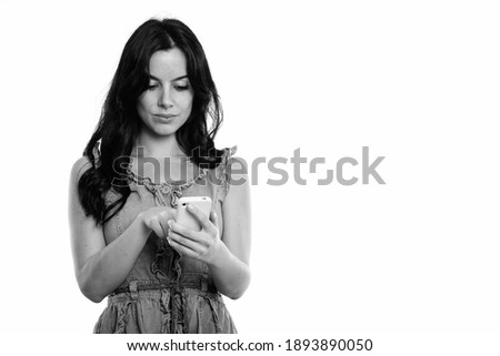 Studio shot of young beautiful Spanish woman using mobile phone