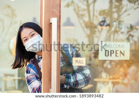 A young girl holding tablet with say hi and have business sign that says 'Welcome we are OPEN' in Coffee cafe shop or Restaurant door. Small businesses and real estate