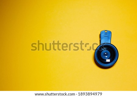 wide angle lens with clothespin for phone on yellow background, mobile creative photography.