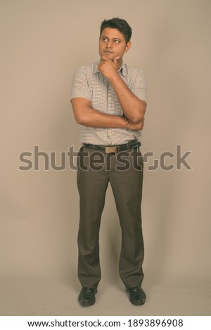 Young Indian businessman against gray background