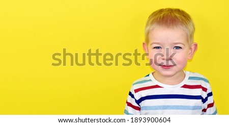 Close up Portrait of a handsome little laughing boy. Adorable small child laughs on yellow background. Cute blonde kid smiling and laughing. Illumination pantone Background. Banner.