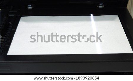 Document scanning process. Scanner in operation scans a sheet of paper with the cover open 4k