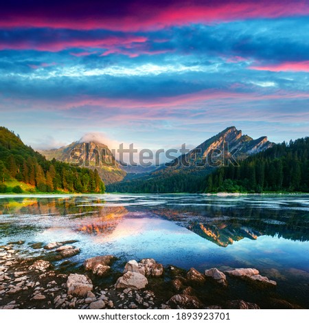Peaceful summer view on Obersee lake in Swiss Alps. Sunrise sky and mountains reflections in clear water. Nafels village, Switzerland. Landscape photography