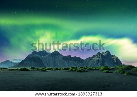 Aurora borealis Northern lights over black sand desert dunes and grassy bumps near famous Stokksnes mountains on Vestrahorn cape, Iceland. Landscape photography. Courtesy of NASA. Photo collage Royalty-Free Stock Photo #1893927313