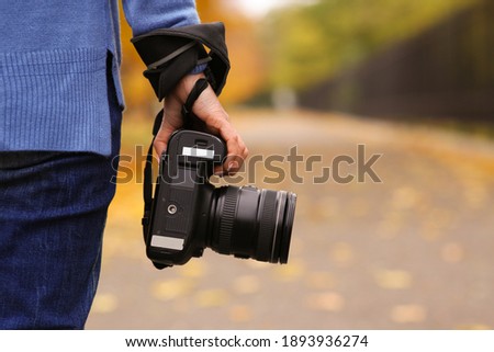 Photographer with professional camera outdoors on autumn day, closeup