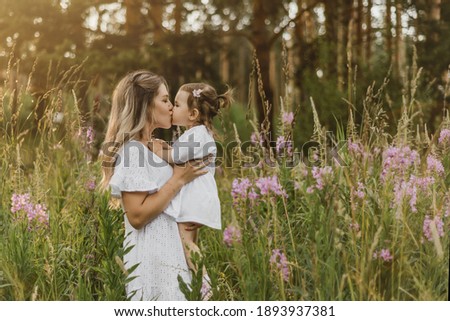 mother with a small child on a background of flowers. mother kisses baby