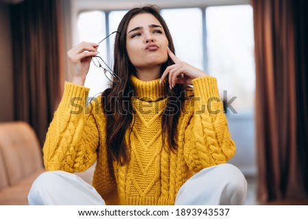 Nice girl wearing glasses and cute sweater is working studying at home. Photo about young freelancer student woman is wondering about something while studying working online.