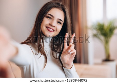 Cute young girl with pretty smile is taking selfie of her at home. Photo about beautiful teen girl at home