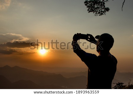 person taking picture at sunset