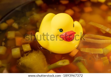 Yellow rubber duck swimming on the soup, duck stock, broth, Vegetable soup