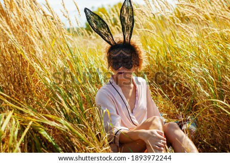Fashion Portrait Of A Young Beautiful Caucasian Blonde Girl In Lacy Mask and in pajamas In Nature Field.
