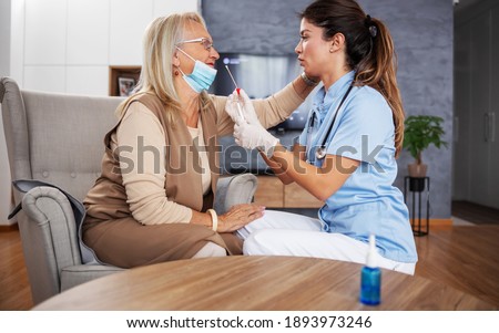Dedicated nurse with sitting at home with senior woman and taking swab from her nose to test her on corona virus.