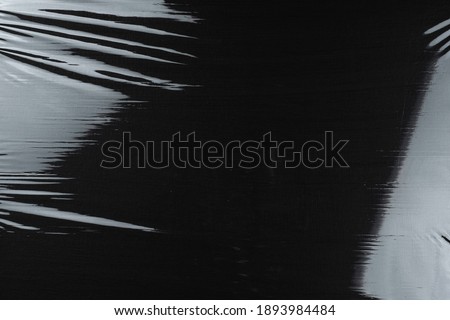 Transparent plastic wrap on the black background. Clean blank texture overlay effect template. Isolated wrinkle surface branding mock-up.