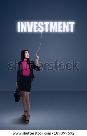 Portrait of businesswoman standing under of investment sign