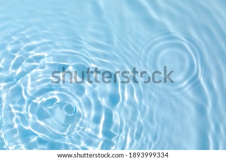 De-focused blurred transparent blue colored clear calm water surface texture with splashes and bubbles. Trendy abstract nature background. Water waves in sunlight with copy space. Royalty-Free Stock Photo #1893999334