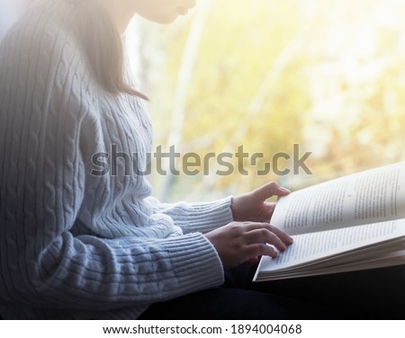 Girl is reading book beside window Royalty-Free Stock Photo #1894004068