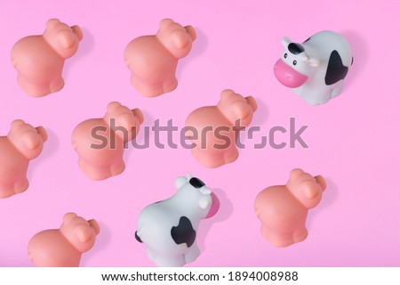 One main cow in front of several small cute pigs and one cow on pastel pink background. Minimal meeting, business, career growth, humor and abstract trendy fresh concept.